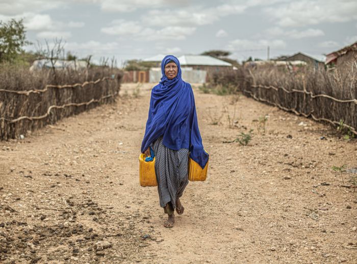 Woman carrying water back to her shelter