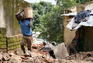 Limbani Paulo carrying a bucket filled with mud removed from his home damaged by Cyclone Freddy in Blantyre southern Malawi