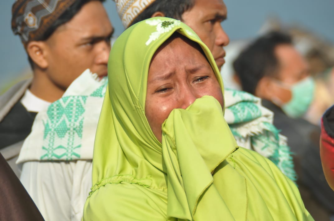 A woman cries as people look at the damages after an earthquake and a tsunami hit Palu, on Sulawesi island on September 29, 2018