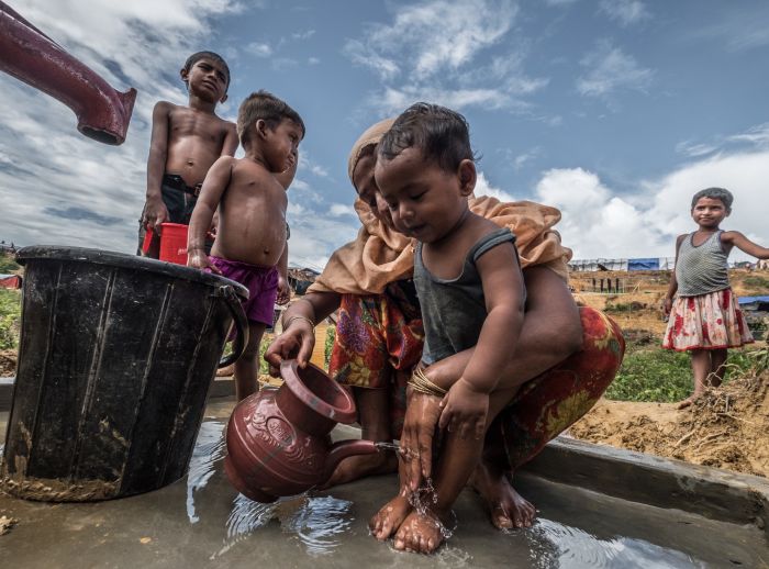 Habiba* washes her son at an Oxfam water pump.