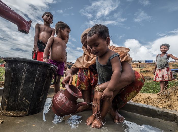 Habiba* washes her son at an Oxfam water pump. 