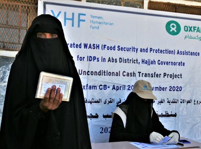 Hind* in distribution centre, holding cash card before receiving cash assistance from Yemen Humanitarian Fund through Oxfam.