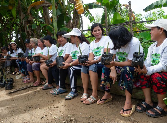 Women’s group members display mangrove saplings they’ve raised in their nursery.