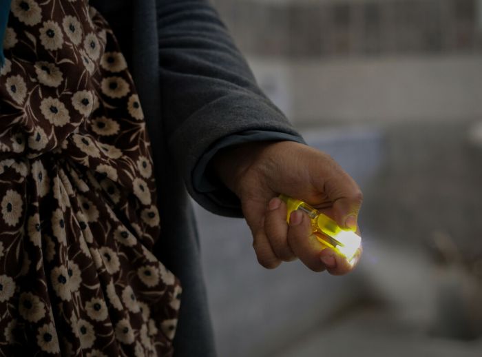Nehal, a displaced woman from Aleppo, holds a flashlight she uses to light the way in the corridors of the shelter where she stays with her two daughters. 