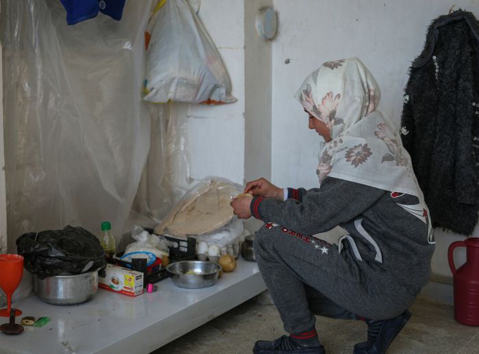 A displaced girl from Aleppo by the earthquake, makes a meal of boiled potatoes and bread