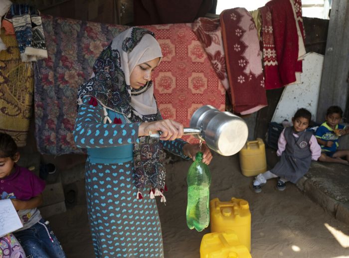 Eilaf, 25, pours water for her children-scr.jpg