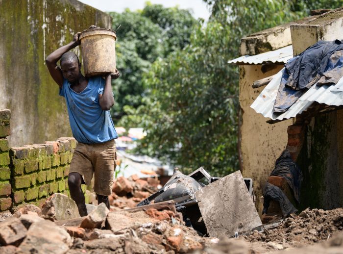 Limbani Paulo carrying a bucket filled with mud removed from his home damaged by Cyclone Freddy in Blantyre southern Malawi