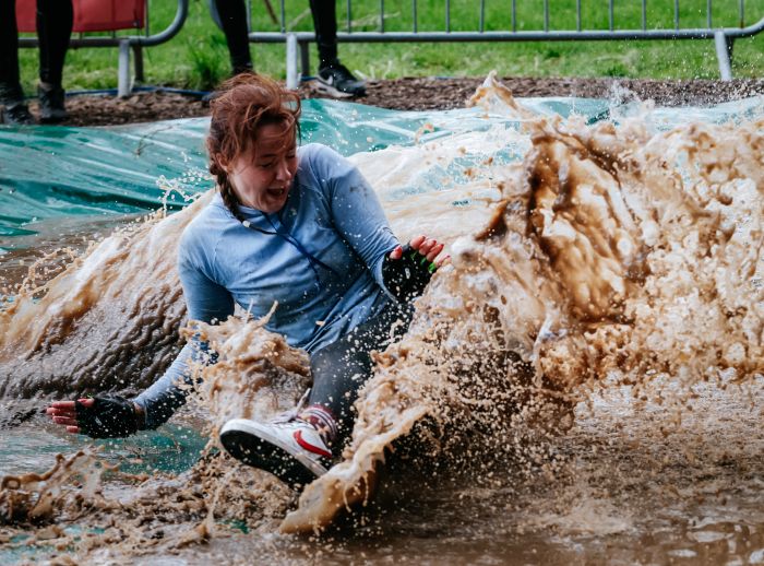 A women sliding in muddy water during the Hell and Back Challenge