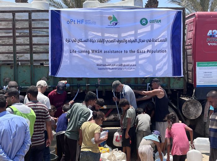 Group of displaced people trying to fill their jerrycans and buckets with water.