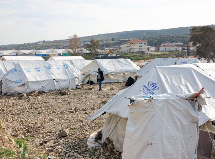 Asylum seekers stand next to tents near the sea at the Mavrovouni camp on Lesbos