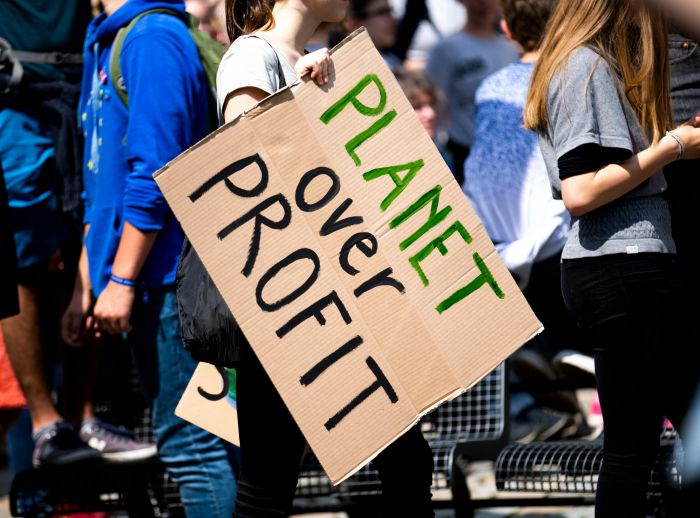 Banner with text "Planet over Profit" held by a person during a demonstration