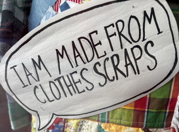 Skirt made of clothes scraps with a sign reading "I am made from clothes scraps"