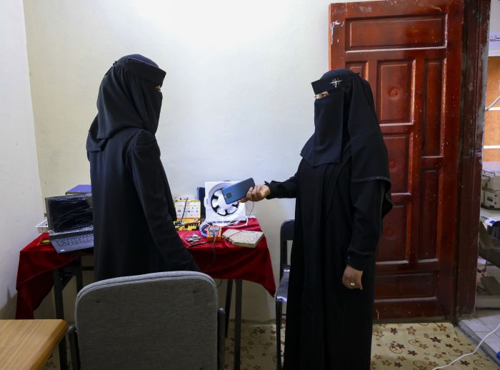 Nahla Abdo and another woman work with electronics in a room.