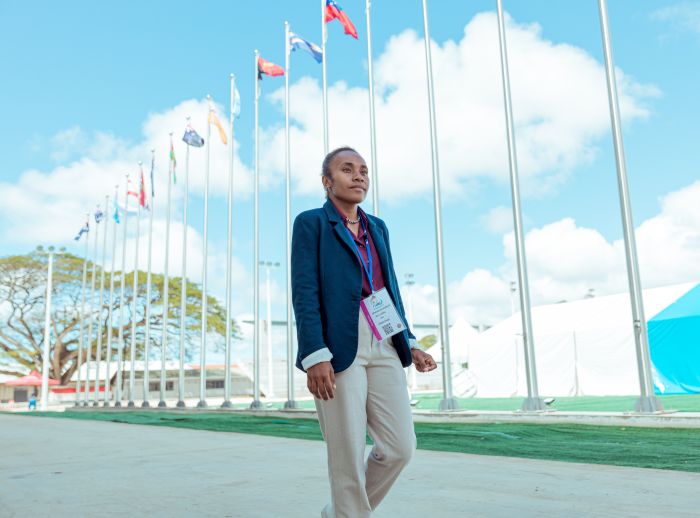 Cynthia Houniuhi at the 53rd Pacific Island Forum Leaders Meeting with flags in the background.