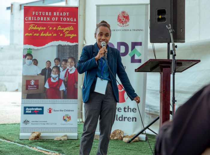 Cynthia Houniuhi speaks at an event in Tonga during the Pacific Island Forum week, with banners and a podium behind her.