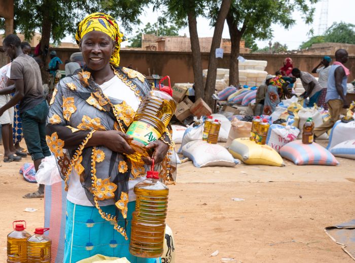 Fatim Somda in Boulsa, Burkina Faso, holds bottles of cooking oil at a food distribution site supported by Oxfam during the lean season.