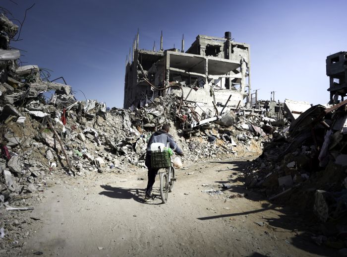 Man cycles his bike in the Gaza ruins.