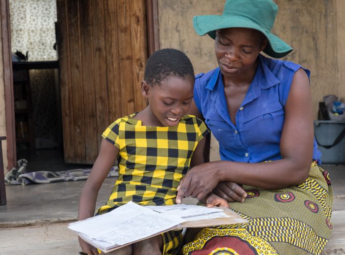 Elizabeth Mutimwii and daughter reading a notebook.