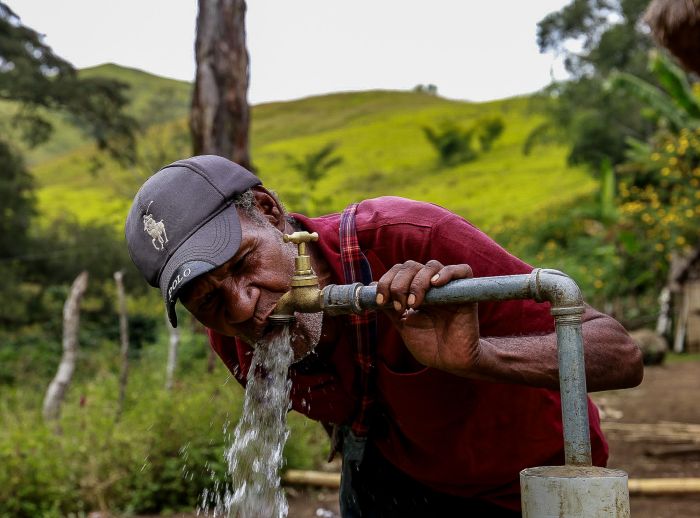Esoi of Nogorunte community in Papua New Guinea (PNG), drinks water from a newly built tap outside his home