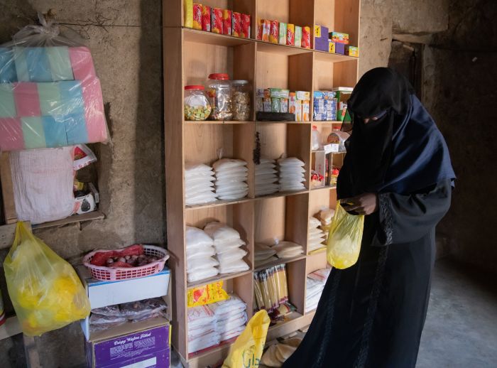 Oqba weighs out kilos of rice at her scales. She ensures each bag is properly weighed and arranged for sale