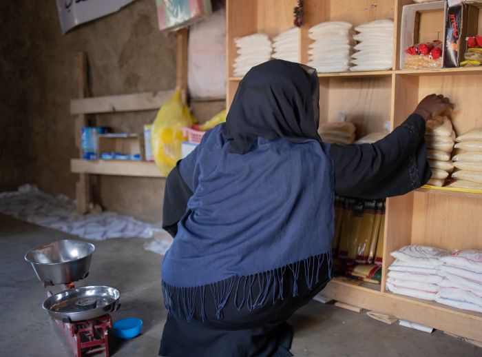 Oqba organises weighed bags of rice on the shelves. She ensures each bag is properly weighed and arranged for sale.