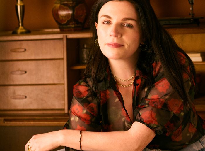Aisling Bea sits on a chair posing for Oxfam Ireland's Second Hand September Campaign.