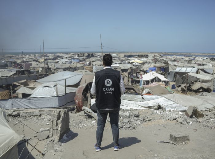 Osama, Oxfam Staff, walks among tents and rubble in Gaza City