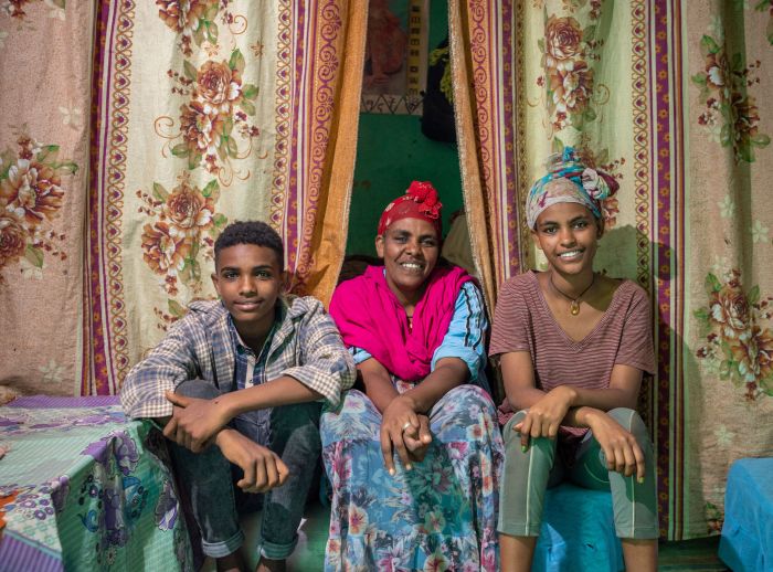 Mebrit Kesaye sits with two of her children in their home.