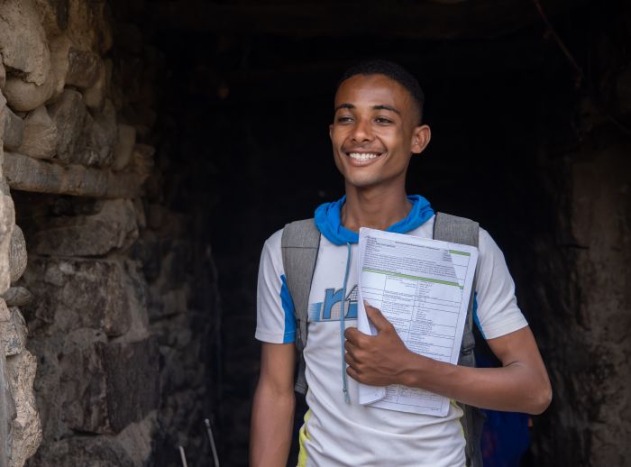 Munadhel smiling with his college books