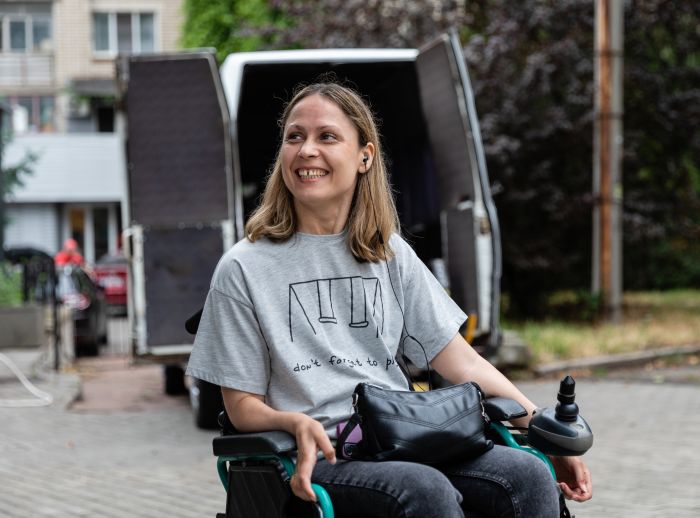 Anastasia* smiles in front of one of the specially equipped taxis her new business will soon provide people with disabilities in Mykolaiv city
