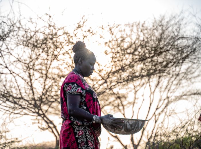 Ann Loutei washes gold mine rock in a metal tray in Turkana County, Kenya