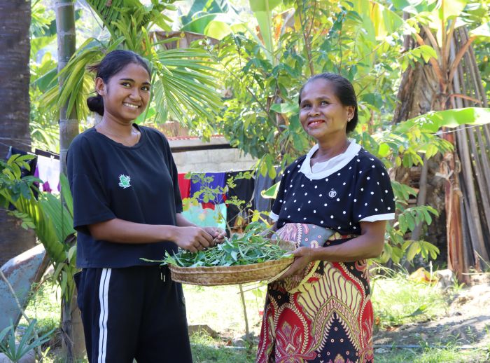 Monica and her daughter harvest water spinach from their home garden. 