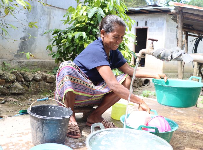 Kornelia "Korrie" Kolo uses clean water, fresh from her Oxfam-partner supplied water tank, to wash dishes outside her home.