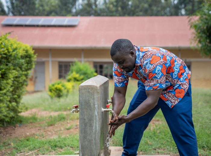 Man washing his hands in a tap outdoors