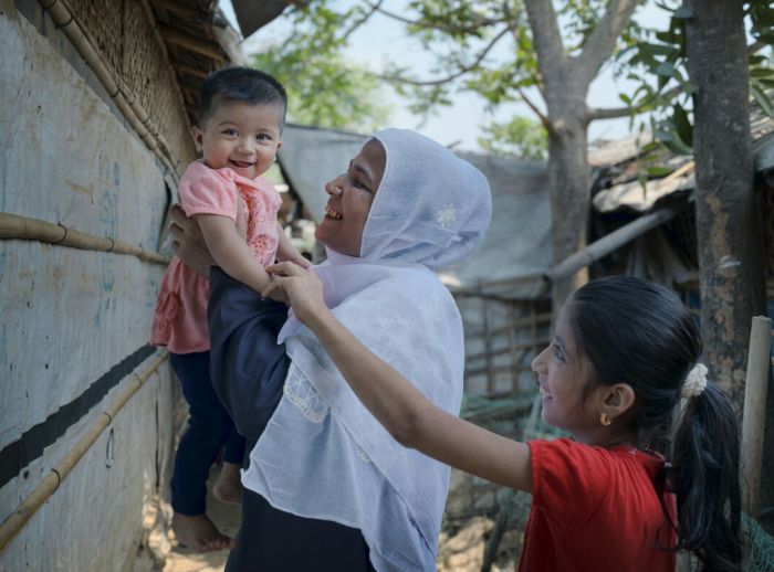Dil smiling with her baby girl and her older daughter