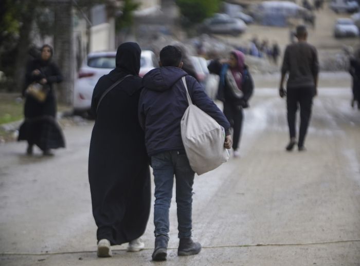 man and woman holding bag walking down road in Gaza