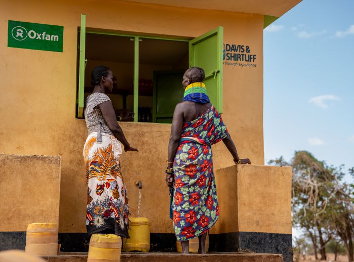 Lydia and Monti, residents, chatting as they fetch water at the water kiosk in Nawamor village.