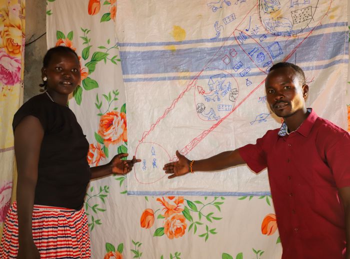Two people stand pointing at a diagram hanging on a wall