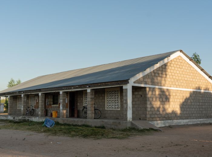 A one-storey brick building in Malawi. Shadows of trees can be seen on its side wall