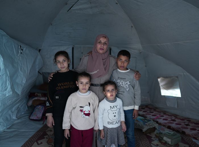 Hiba and four children stand inside a tent