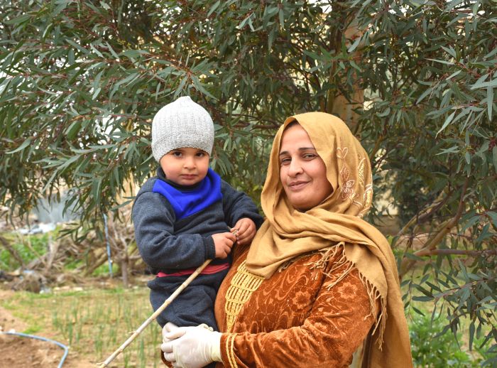 woman holds her son on farm in rural Syria
