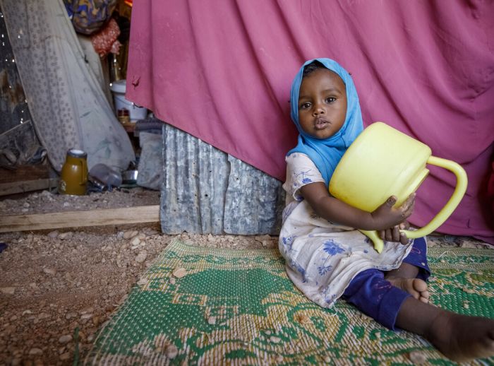 young child holding empty water jug