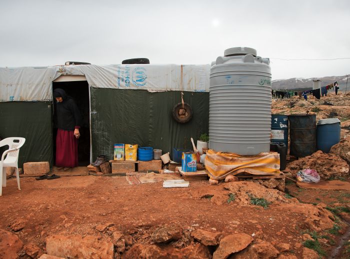 woman stands in her provisional shelter