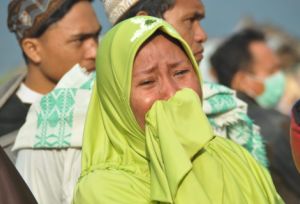 A woman cries as people look at the damages after an earthquake and a tsunami hit Palu, on Sulawesi island on September 29, 2018