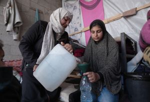 Two women filling up water bottles