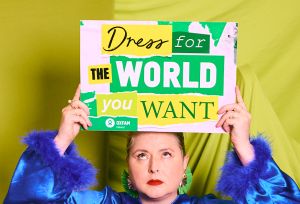Siobhan McSweeney holding Oxfam's signs "Dress for the world you want" and "Second hand September"