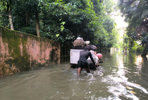 Man in Bangladesh pushing a cart in a flooded street - water up to his knees.
