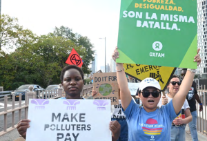 Climate activists Hilda Nakabuye and Marinel Ubaldo join a climate march in New York in September 2024. Signs read "Make Polluters Pay" 