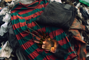 Image of Freddy Krueger Halloween outfit on top of a pile of clothes in the landfill.AI generated content.