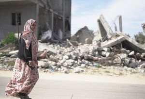 A woman walking in the street of Gaza surrounded by rubbles